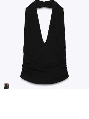 Svart halterneck topp med djup v-ringning - Snygg svart halterneck topp med djup v-ringning och omlottkänsla. Toppen är ärmlös och har en smickrande passform med lätt rynkade sidor. Perfekt för att skapa en cool och stilren look.