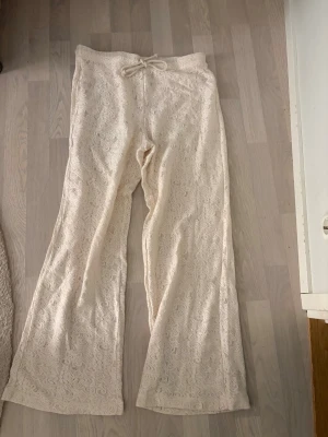 Beiga spetsbyxor från Kappahl M - Säljer ett par beiga byxor från Kappahl i storlek M. Byxorna har ett snyggt spetsmönster över hela och är utrustade med snörning i midjan. Modellen är rak och har en loose passform, vilket gör dem riktigt sköna och trendiga. Oanvända. Storleken upplevs mer som L - XL