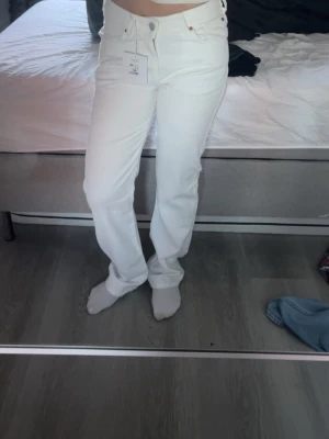 Vita raka jeans med låg midja  - Säljer ett par fräscha vita jeans med rak passform och låg midja. Byxorna har klassiska fem fickor, knapp och dragkedja framtill samt bälteshällor. Materialet är jeans och de är perfekta för dig som gillar en clean och stilren look. Säljer då jag fick i julklapp men är för små för mig.