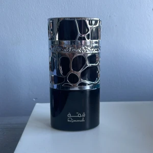 Qimmah elegant parfymflaska - Snygg parfym från Qimmah med unik design och stilren look. Perfekt för dig som vill sticka ut och ha något annorlunda i din samling. Flaskan har coola detaljer i silver och svart. Volym och ingredienser framgår ej på bilderna.