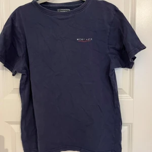Mörkblå t-shirt från McKenzie - Snygg mörkblå t-shirt från McKenzie med diskret logga på bröstet. Klassisk rund hals och korta ärmar. Tillverkad i mjuk bomull som känns skön mot huden. Perfekt för dig som gillar enkel och stilren design. Storlek XL för barn. Passar S och M. 