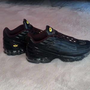 Nike Air Max Plus Tn helsvarta sneakers - Säljer ett par Nike Air Max Plus Tn i helsvart med coola detaljer och synlig luftdämpning i sulan. Skorna har snörning, Tn-logga på hälen och mesh- samt syntetpaneler för en futuristisk vibe. Perfekta för dig som gillar streetwear och vill sticka ut. Passar bra nu till vinter, tvekan inte på att fråga!! Ny pris 3299kr