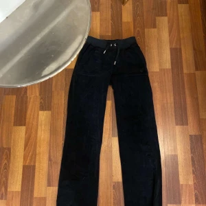 Svarta  Juicy Couture byxor XXS - Svarta byxor från Juicy Couture i storlek XXS. Byxorna har resårmidja med snörning och raka ben. Fickor fram och bak med knappdetaljer. Perfekta för en chill och snygg look. Jätte sköna!