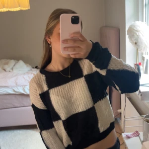 Svartvit rutig stickad tröja Vero Moda - Säljer en stickad tröja från Vero Moda i storlek XS. Tröjan har ett stort rutigt mönster i svart och beige, med rund halsringning och långa ärmar. Perfekt för dig som gillar en trendig och mysig look.