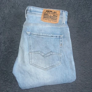 Replay jeans Rocco W31 L34 - Säljer ett par ljusblå jeans från Replay, modell Rocco. Klassisk femficksdesign, raka ben och snyggt Replay-märke bak i midjan. Jeansen är tillverkade i bomull och har en stilren, enkel look som passar till det mesta. Midja 42cm, längd 110cm. 