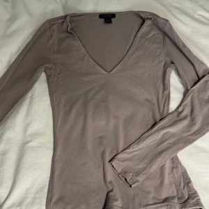 Beige långärmad v-ringad topp Amisu - Säljer en beige långärmad topp från Amisu/new yorker med snygg v-ringning. Modellen är figurnära och mjuk och skön i materialet.