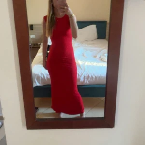 Röd långklänning ärmlös - Säljer en snygg röd långklänning med ärmlös design och rund halsringning. Klänningen har en figurnära passform som framhäver siluetten och är perfekt för dig som gillar stilrena och enkla plagg. Passar dig som vill sticka ut med färg.