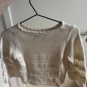 Vit stickad tröja med spetsdetaljer - Superfin vit stickad tröja från Only med snygga spetsdetaljer och mönstrade partier. Tröjan har lång ärm och en lite croppad passform som ger en modern vibe. Perfekt att styla med jeans eller kjol för en chill look.