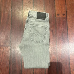 Grå jeans från Jack & Jones, 30/30 - Snygga grå jeans från Jack & Jones i klassisk femficksmodell. Jeansen har raka ben och normal passform, tillverkade i mjukt bomullstyg med en stilren look. Perfekta för dig som gillar en enkel och clean stil.