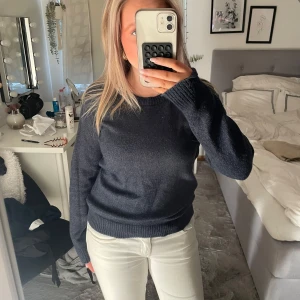 Mörkblå stickad tröja från Vila - Mysig mörkblå stickad tröja från Vila med rund halsringning och ribbade muddar vid ärmslut och nederkant. Enkel och stilren modell som är perfekt för lager-på-lager. Passar dig som gillar en klassisk look med en chill vibe.