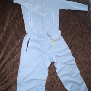  Nike tech  - Snygg ljusblå hoodie från Nike med vit logga på bröstet. Tröjan har dragkedjor på fickorna och långa ärmar. Perfekt för chill eller träning, tillverkad i mjuk bomullsblandning för extra komfort.