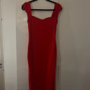 Röd långklänning med slits - Snygg röd långklänning med breda axelband och en smickrande v-ringad urringning. Klänningen har en rak passform och en slits baktill. 