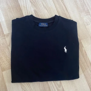  t-shirt från Polo Ralph Lauren - Svart t-shirt från Polo Ralph Lauren med klassisk passform och korta ärmar. Ikonisk vit broderad logga på bröstet. Tillverkad i mjuk bomull och har rund halsringning. Perfekt basic-plagg med stilren look.