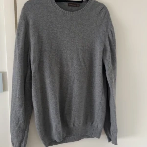 Grå Kashmir tröja från Oscar Jacobson - En stilren grå stickad tröja från Oscar Jacobson i storlek XL men passar L. Tröjan har rund halsringning, ribbade muddar och är tillverkad i kashmir material. Perfekt för olika passande outfits.