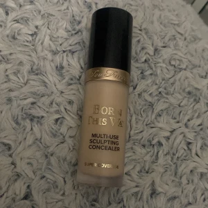 Too Faced Born This Way Concealer Swan - Multi-use sculpting concealer från Too Faced i nyansen Swan. Kommer i en frostad glasflaska med svart och guld lock. Perfekt för att täcka, highlighta och konturera. Ger supertäckning och har en krämig formula.Advänd  6 gångar, inga skador. 