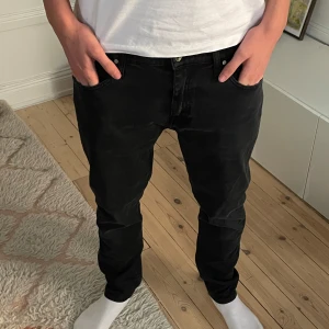 Svarta jeansbyxor från tiger of sweden - Svarta tiger of sweden jeans med klassisk femficksdesign och smal passform. Jeansen har normal midja och raka ben, tillverkade i stretchig bomullsdenim för extra komfort. Perfekta för en clean och stilren look.