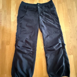Svarta danspants lowwaist från Nike - Svarta dans-/träningsbyxor från Nike med elastisk midja, stora fickor på benen.  Byxorna har avslappnad passform och resår vid benslut. Perfekta för en sportig och chill stil. Låga i midjan. 