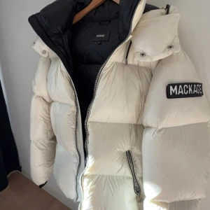 Vit pufferjacka från Mackage - Säljer en riktigt fet vit pufferjacka från Mackage med svart innerfoder och stor huva. Jackan har dragkedjor på fickorna och en tydlig Mackage-logga på ärmen. Perfekt för kalla dagar när du vill hålla stilen och värmen. Nypris på 10k mitt pris 4k priset kan diskuteras vid snabb affär.  Bag till jackan finns och special gjord galje för att hänga upp jackan rätt finns!!!