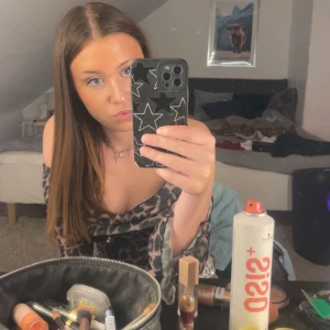 Leopardmönstrad offshoulder topp - Säljer en snygg offshoulder topp med leopardmönster i beige och svart. Toppen har långa ärmar med volangdetalj vid ärmslut och en figurnära passform. Perfekt för dig som vill sticka ut med ett trendigt djurmönster.