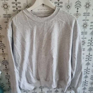 Ljusgrå basic sweatshirt - Enkel och stilren ljusgrå sweatshirt med rund halsringning och långa ärmar. Perfekt för en avslappnad look och lätt att matcha med andra plagg. Mjuk och bekväm, passar året runt.
