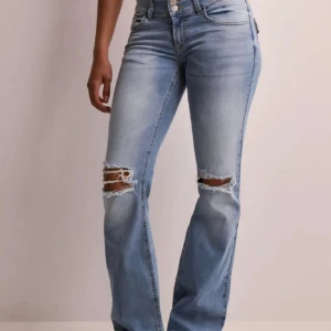 Nelly Ljusblå bootcut jeans med slitningar - Säljer ett par ljusblå jeans med bootcut passform och snygga slitningar över knäna. Jeansen är använda fåtal gånger och är i fint skick, de har några super små defekter som verkligen inte syns, skriv om frågor! Säljer pga att de är lite för stora för mig (köpte en storlek för stort). Originalpris: 699kr💕