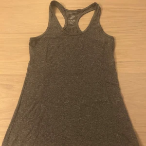 Mörkgrå linnetopp från 157 Funk - Säljer en mörkgrå linnetopp från 157 Funk i storlek small. Toppen är ärmlös med brottarrygg och tillverkad i mjuk polyester, perfekt för träning eller chill dagar. Enkel och stilren design som är lätt att matcha med andra plagg.