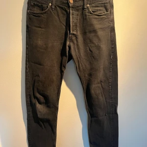 Svarta Jack & Jones jeans  - Svarta jeans från Jack & Jones med klassisk femficksdesign. Jeansen har en smal siluett, normal midja och är tillverkade i mjukt denimtyg med lite stretch för extra komfort. Perfekt för dig som gillar en modern och stilren look.