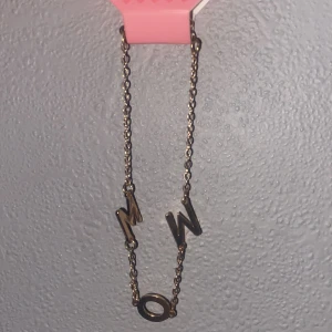 Guldigt halsband med bokstäver - Unikt halsband i guldfärgad metall med bokstäverna M, O och W som hänger på en tunn kedja. Perfekt för dig som gillar personliga detaljer och vill sticka ut med ett coolt smycke. Snyggt att matcha med andra halsband för en trendig look.