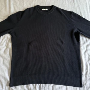 Ribbad Zara Tröja  - Mörkblå stickad tröja från Zara med rund hals och långärmade ribbade muddar. Tröjan har en clean och enkel design med diskret struktur i materialet, perfekt för dig som gillar minimalistisk stil. Passar dig som vill ha en klassisk look.