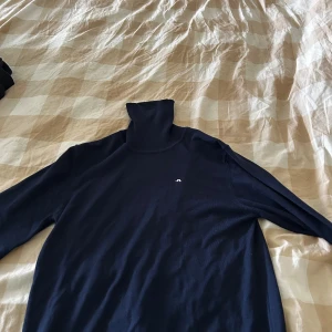 Mörkblå polotröja från J.Lindeberg - Snygg mörkblå polotröja från J.Lindeberg med diskret logga broderad på bröstet. Tröjan är stickad i mjukt material och har lång ärm samt klassisk polokrage. Perfekt för dig som gillar stilrena och tidlösa plagg. Aldrig använd bara tvättad. Pris går att diskutera 