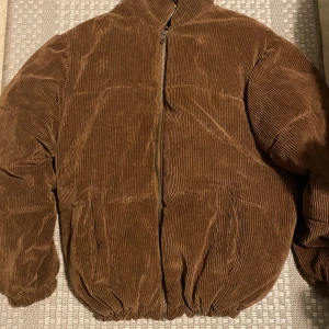 Brun manchester pufferjacka Nova Men - Säljer en brun pufferjacka från Nova Men i grov manchester med dragkedja framtill. Jackan har långärmade ärmar, ribbade muddar och två fickor. Insidan är fodrad med slätt tyg för extra komfort. Perfekt för dig som gillar retrovibe och vill sticka ut.