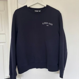 Mörkblå sweatshirt från Björn Borg - Snygg mörkblå sweatshirt från Björn Borg i storlek S. Tröjan har rund hals, långa ärmar och ett stilrent tryck med Björn Borg 1956 på bröstet. Mjuk insida och klassisk passform, perfekt för chill eller sportiga dagar. Köpt på Ullared