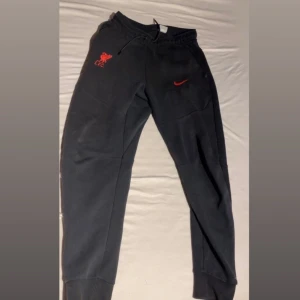 Svarta Nike tech fleece Liverpool byxor - Jättesnygga Nike tech byxor med Liverpool loggan på. Inga defekter och dragkedjan funkar jättebra. Snörena är kvar och inte urtvättade. Skicka gärna prisförslag!