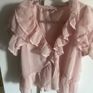 Ljusrosa volangblus med v-ringning - Supersöt ljusrosa blus med v-ringning från Nelly! Fint skick!!