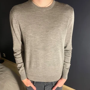 Grå ulltröja - Snygg grå tröja från Uniqlo i 100% ull. Tröjan är storlek M och modellen på bilden är 188 och väger 68. Det finns ett litet hål vid nedre delen av vänstra armen men det går att lösa med lite tråd och en nål. Kom dm för fler bilder eller om du har en fråga osv. 🤗
