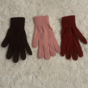 Tre par stickade basic fingervantar - Tre par stickade vanliga fingervantar i olika färger: ett par mörkbruna, ett par ljusrosa och ett par vinröda. 