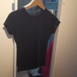 Svart t-shirt från Gina Tricot - En basic svart t-shirt från Gina Tricot i storlek S. Modellen är klassisk med rund halsringning och korta ärmar. Perfekt att matcha med jeans eller kjol. Materialet känns mjukt och skönt mot huden.