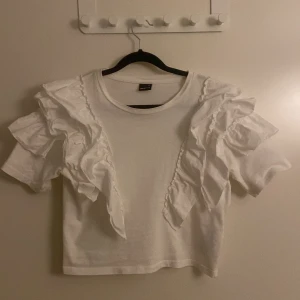 Vit croppad topp med volanger - Superfin vit croppad topp från Gina!! Är som ny då jag andvänt den max två gånger😊
