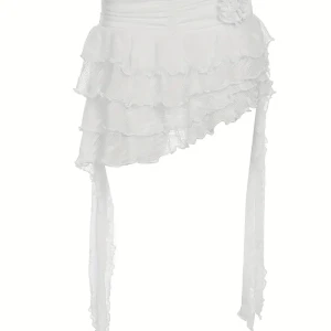 Vit asymmetrisk volangkjol med rosett S - Supersöt vit kortkjol med flera lager volanger och asymmetrisk form. Kjolen har långa dekorativa band på sidorna och en rosett vid midjan. Tillverkad i lätt, skrynkligt tyg som ger en luftig känsla. Perfekt för dig som gillar unika detaljer och romantisk stil.