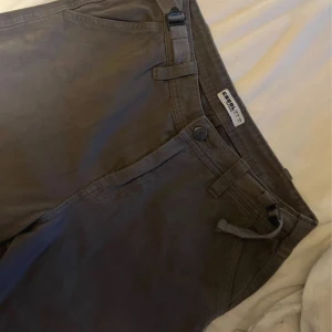 Mörkgråa cargopants  - Snygga mörkgråa cargopants  med praktiska fickor på benen och justerbara band i midjan. Byxorna har en rak passform, använd några fåtal gånger men används inte längre då dom är för små
