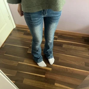 Blå bootcut jeans med ljus tvätt - Snygga blå jeans med bootcut passform och ljus tvätt på framsidan. Klassisk femficksmodell med normal midja och raka ben som blir vidare nedtill. Jeansen har tydliga sömmar och är tillverkade i jeansmaterial med en mjuk känsla.
