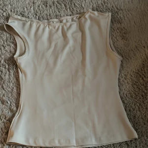 Vit ärmlös linnetopp  - Säljer en stilren vit linnetopp med rund halsringning och ärmlös design. Toppen har en slät och enkel look som passar perfekt till jeans eller kjol. Materialet känns mjukt och lätt mot huden. Strl S men har ingen etikett vart den är ifrån!!