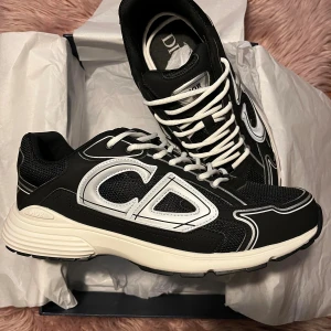 Dior skor - Snygga svarta Dior sneakers med stora reflekterande CD-detaljer på sidorna. Skorna har vit sula, vita snören och är tillverkade i en mix av mesh. Skorna är helt nya och aldrig använda 