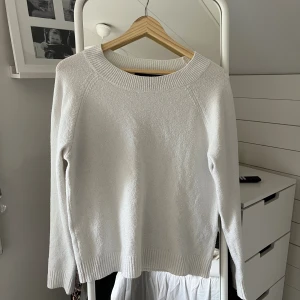 Vit stickad tröja med rund hals - Säljer en enkel och fräsch vit stickad tröja med rundad hals och ribbade muddar vid ärmslut och nederkant. Perfekt för lager-på-lager och passar till jeans eller kjol. Långärmad och mjuk i materialet.