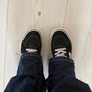 Svarta Vans Sk8-Hi sneakers - Säljer ett par klassiska Vans sneakers i svart mocka med vita detaljer och snörning. Skorna har en vit sula, rund tå och den ikoniska sidostripen i vitt. Perfekt för dig som gillar streetstyle eller sthlmstil och vill ha en snygg och tidlös look.💕💕💕