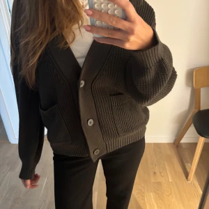 Mörkgrön stickad kofta med knappar - Säljer en mörkgrön stickad kofta med stora knappar framtill från märket MINIMUM. Koftan är i storlek S/M och är helt oanvänd💞