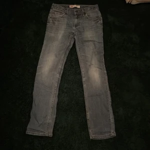 Levi's 511 grå jeans straight fit - Snygga grå jeans från Levi's modell 511 med klassisk femficksdesign och raka ben. Jeansen har en cool tvättad look och är tillverkade i mjukt jeanstyg som sitter skönt. Passar dig som gillar en enkel och stilren vibe.
