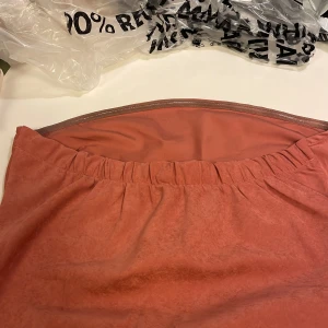 Rostfärgad midiklänning med bandeau-ringning - Säljer en snygg rostfärgad klänning från asos  känningen har regular fit passform och är tillverkad i ett mjukt syntetmaterial med lätt stretch.. Perfekt för dig som gillar minimalistisk stil och jordnära färger.