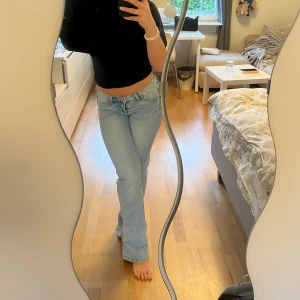 Ljusblå bootcut jeans  - Säljer ett par ljusblå jeans med bootcut passform och låg midja. Jeansen är i stretchigt material med ett hål på ena benet. Köpta från H&M