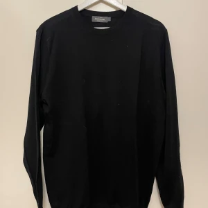Svart merinoulltröja - Klassisk svart tröja i merino ull från Dressmann i mjuk merinoull. Rund halsringning och långärmad modell med ribbade muddar vid ärmslut och nederkant. Oanvänd